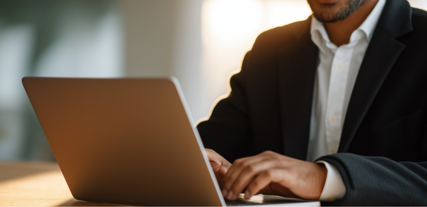 A member in a dark suit working at a laptop in warm evening light